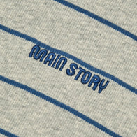Close-up of a Main Story Rolled Neck melange gray organic cotton fabric with  blue stripes and 'MAIN STORY' embroidered in blue thread.