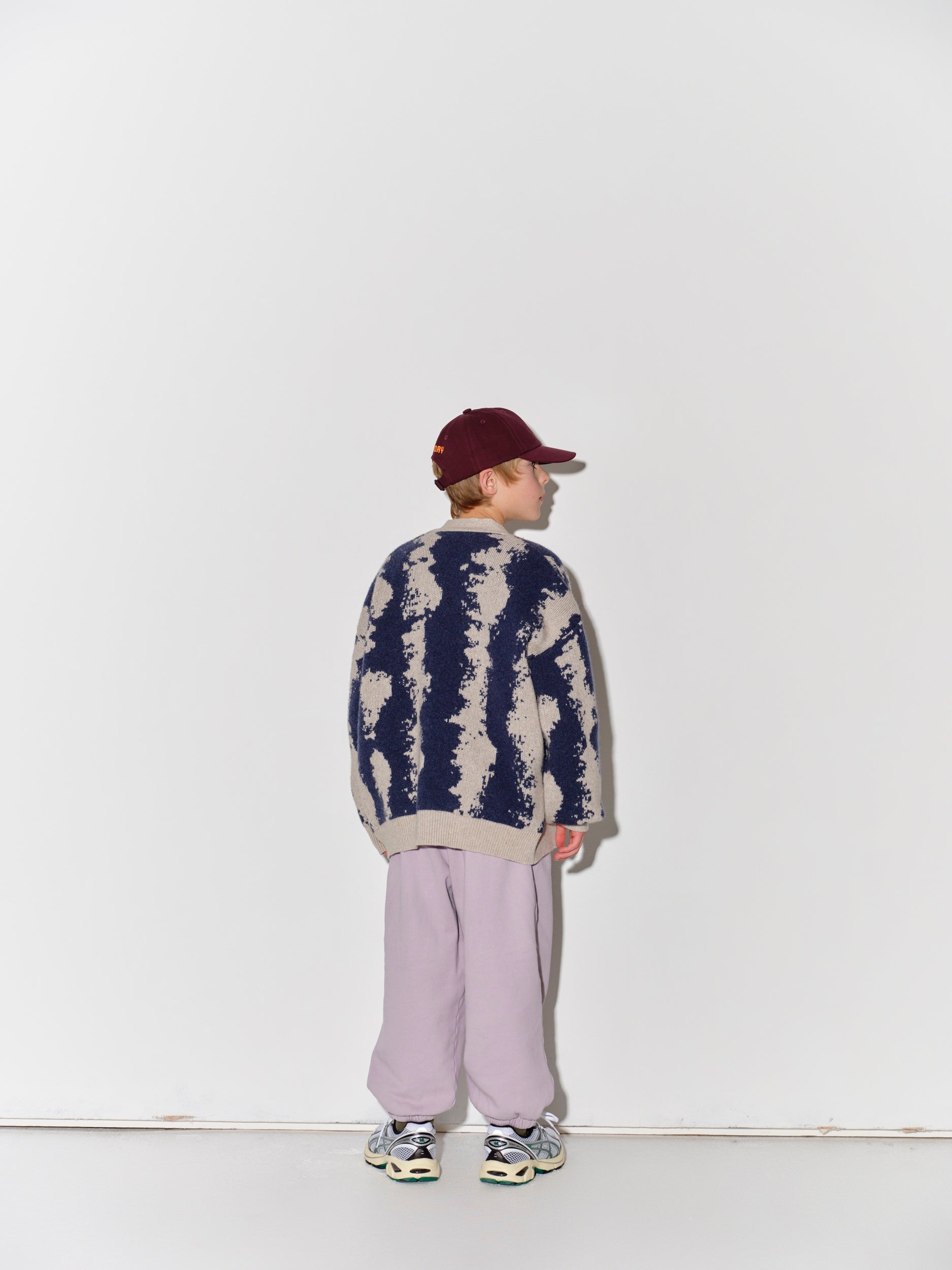 Child wearing a Main Story knit cardigan, striped shirt, and light purple pants
