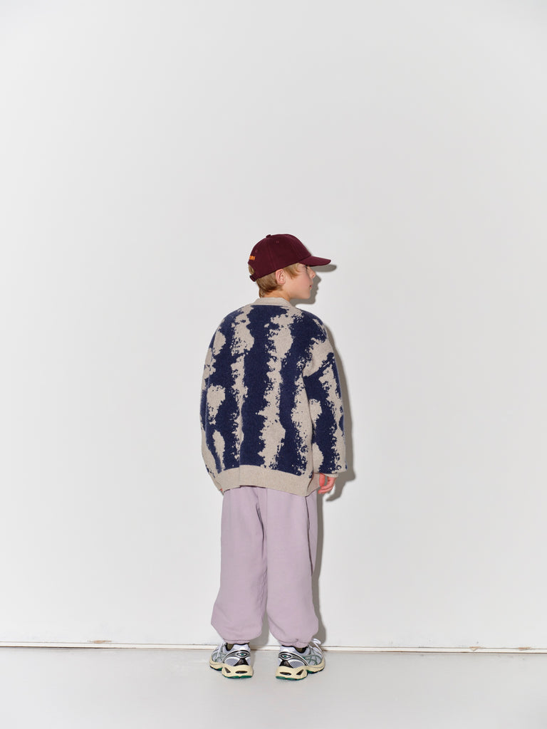 Child wearing a Main Story knit cardigan, striped shirt, and light purple pants