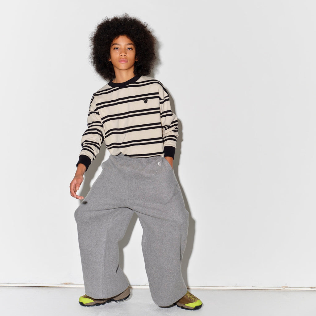 Kid wearing a Main Story long sleeve band tee with ivory and black stripes and gray  sweatpants