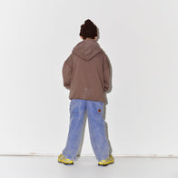 Kid wearing a Main Story dark brown knit beanie, falcon brown hoodie, blue denim overalls, and yellow shoes on a white background