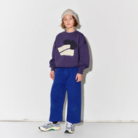 Child wearing a purple sweater with a graphic design and Main Story blue painter cargo pants