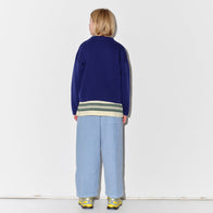 Person wearing a Main Story blue sweatshirt, striped t-shirt, and light dusty blue corduroy lounge pants with yellow sneakers