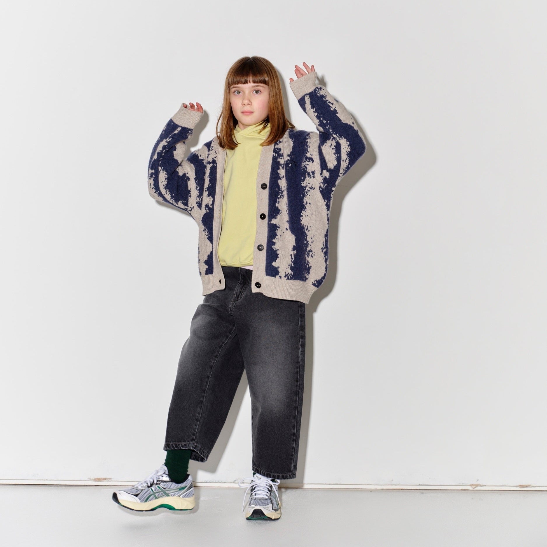 Child wearing Main Story knit cardigan in oat/navy with faded baggy black jeans