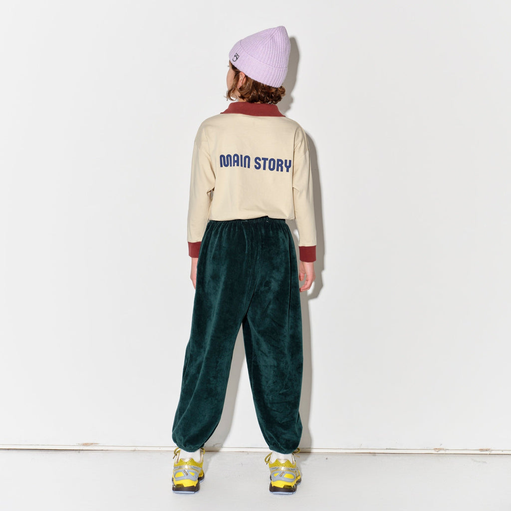 Kid wearing a Main Story beige athletic long sleeve polo tee, green jogger pants, and yellow shoes