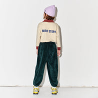 Kid wearing a Main Story beige athletic long sleeve polo tee, green jogger pants, and yellow shoes