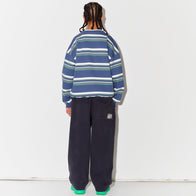 Child wearing a Main Story blue striped sweatshurt and dark grey lounge pants with green shoes