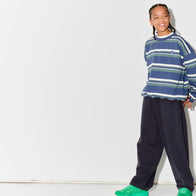 Child wearing a Main Story blue striped sweatshurt and dark grey lounge pants with green shoes