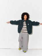 Child wearing a Main Story bottle green teddy fleece jacket, striped tshirt, and gray sweatpants