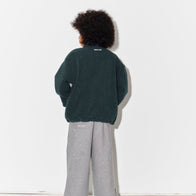 Child wearing a Main Story bottle green teddy fleece jacket, striped tshirt, and gray sweatpants