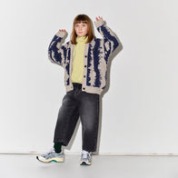 Child wearing a patterned Main Story knit cardigan over a yellow shirt with faded baggy black jeans